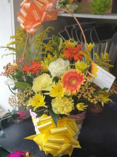 A vibrant arrangement of yellow and orange flowers with decorative bows.