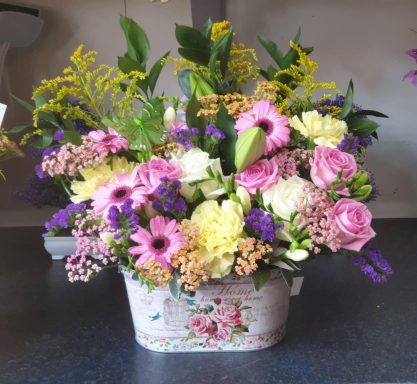 A vibrant floral arrangement with pink and white blooms, greenery, and yellow accents.