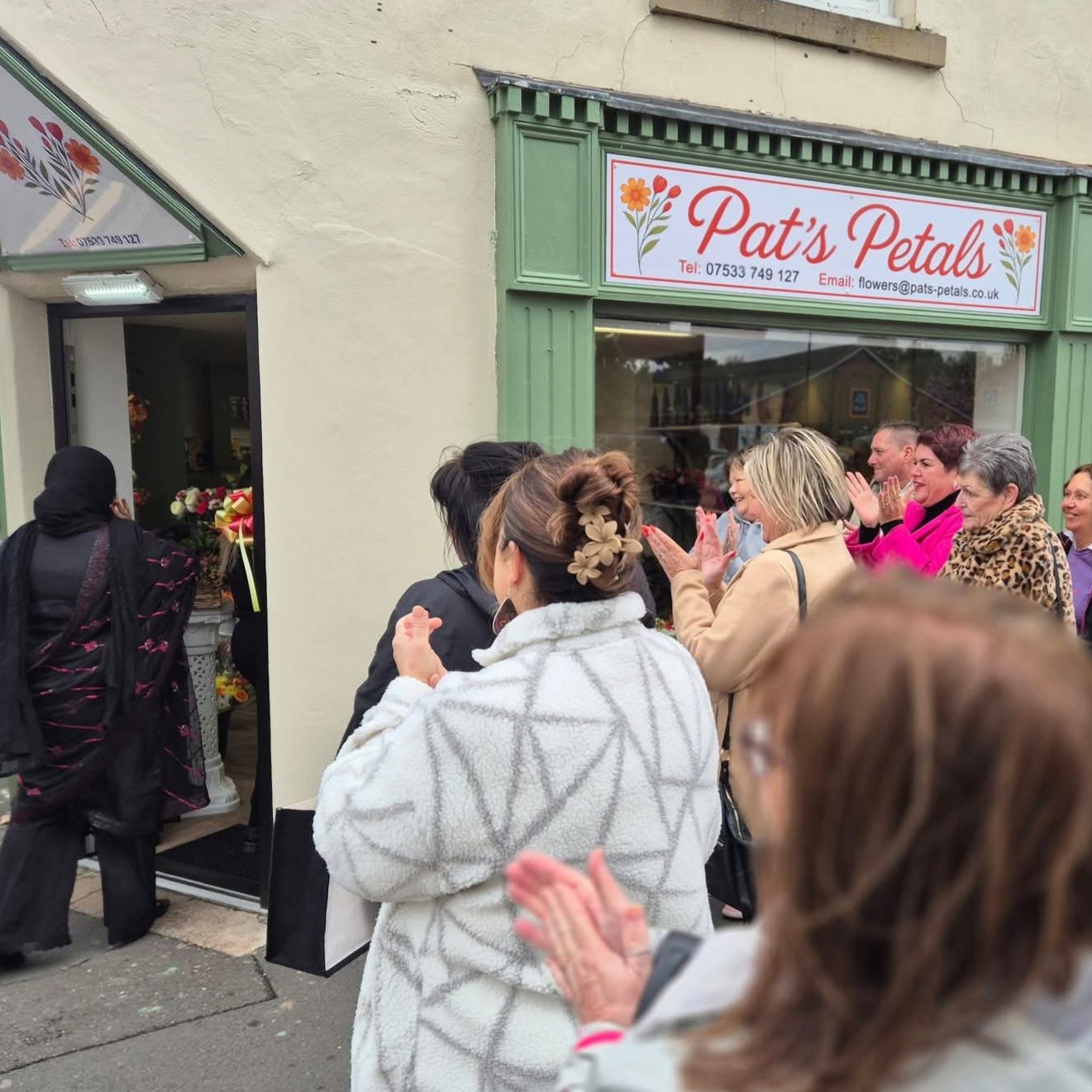 A crowd of people gathered outside Pat's Petals flower shop.