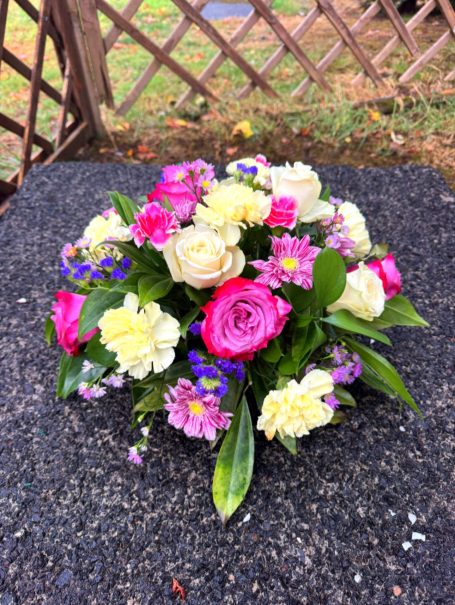 A vibrant floral arrangement with pink, white, and purple flowers on a grey surface.
