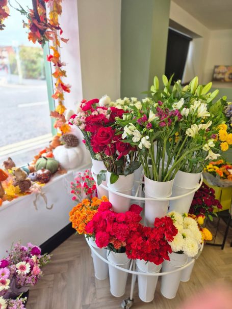 A flower display with various brightly coloured blooms in white buckets.