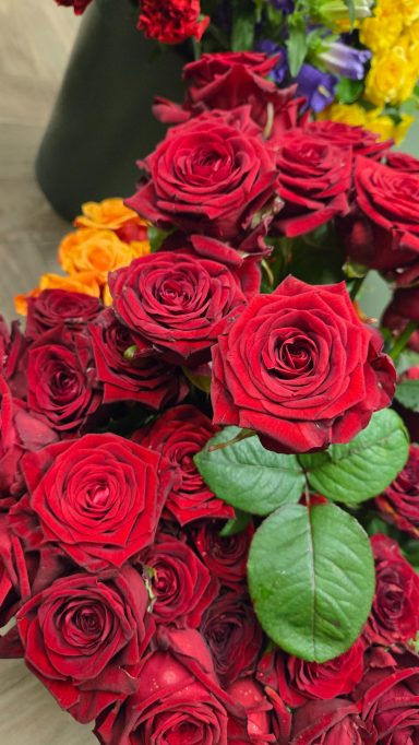 Vibrant red roses with lush green leaves, arranged beautifully.